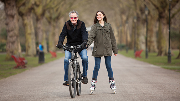 father-and-daughter-biking-and-skating-on-park-trail-and-exercising-after-ostomy-surgery